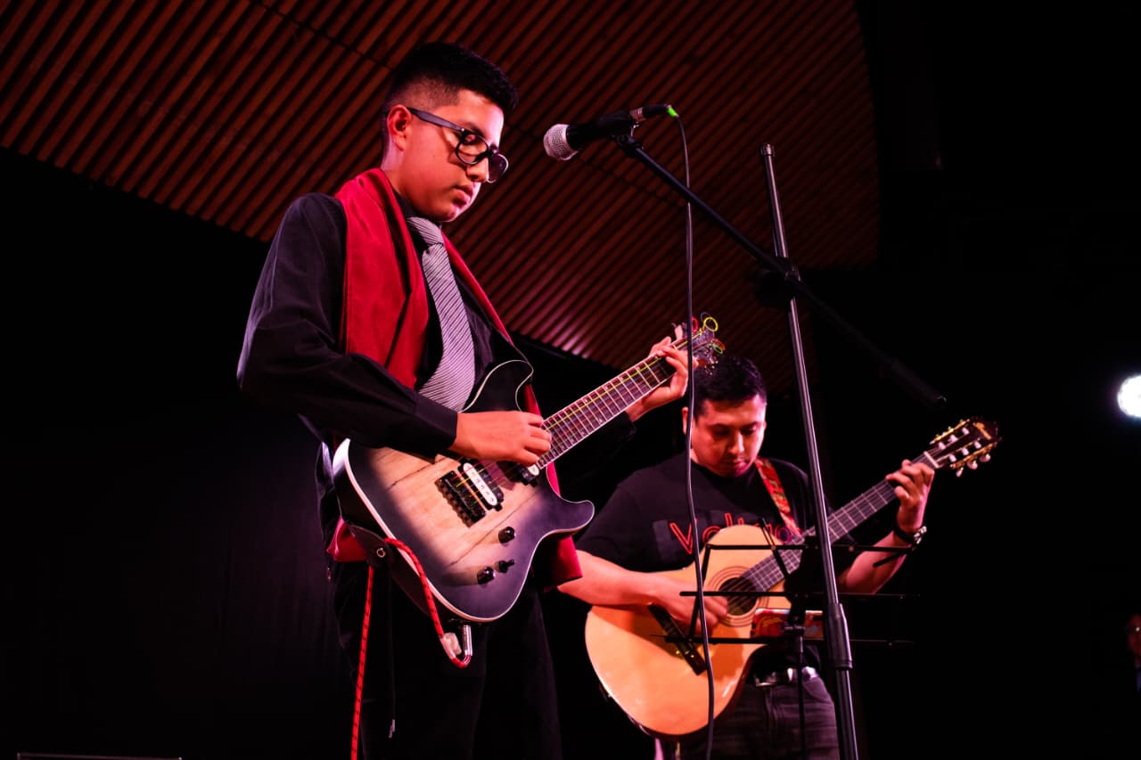 Estudiante y músico tocando guitarras juntos en el escenario