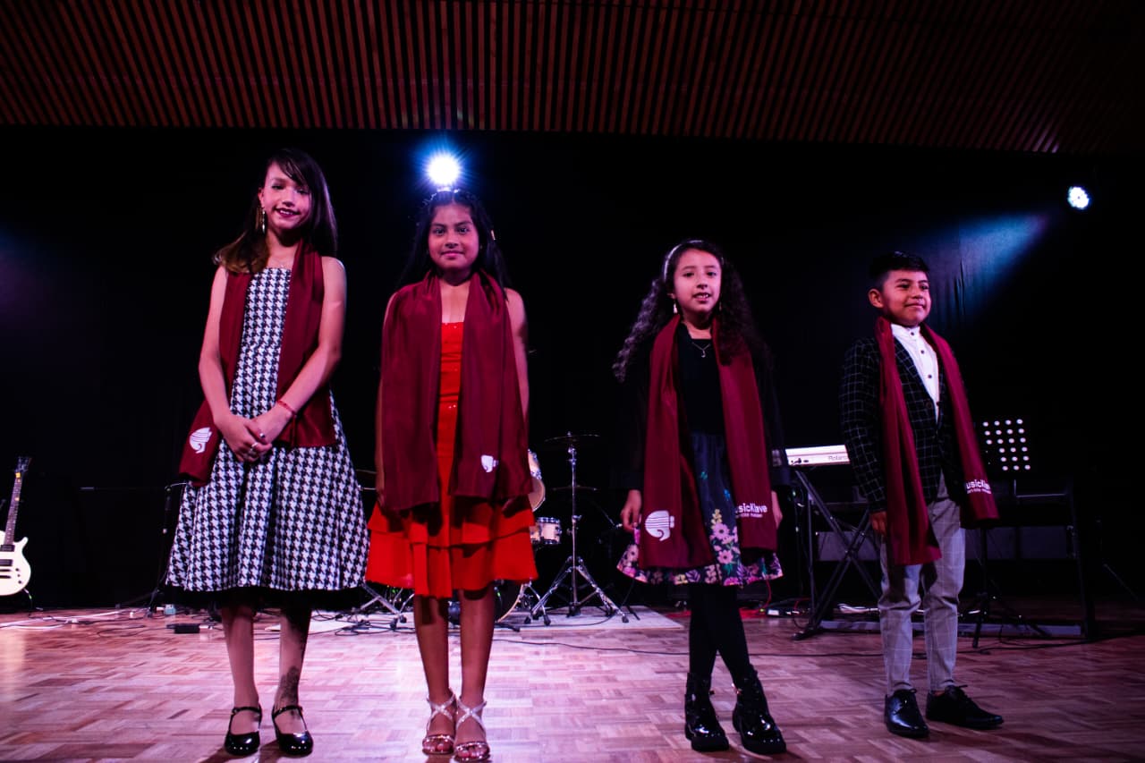 Cuatro estudiantes de MusicKlave compartiendo una presentación en el escenario