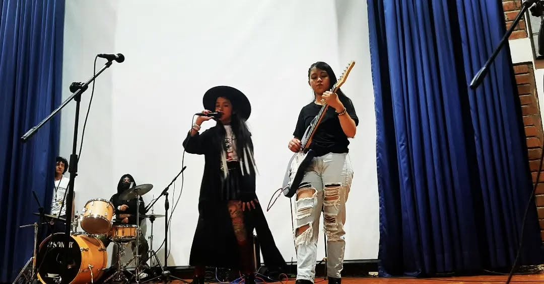 Cantante y guitarrista compartiendo escenario con una banda